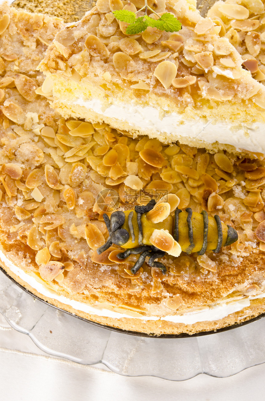 带有杏仁和糖涂层以及奶油或奶油的扁蛋糕咖啡餐饮蜜蜂蜂蜜派对香草馅饼糕点蜡烛饼干图片