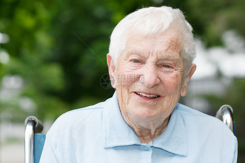 坐在轮椅上快乐的高级女士女性退休祖母人脸老年奶奶树木蓝色长老绿色图片