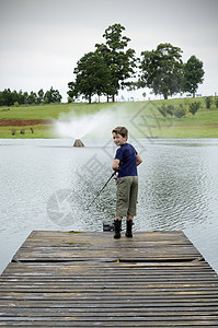 坐着钓鱼男孩男孩在大坝或湖码头捕鱼运动池塘孩子们孩子男性渔夫娱乐乐趣童年青年背景