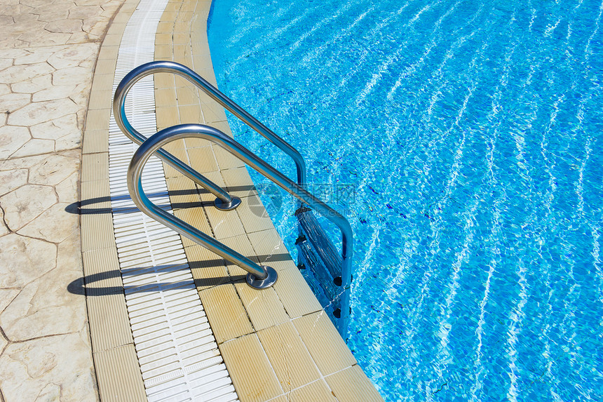 在游泳池中抓铁条梯子反射金属安全闲暇游客假期泳池太阳活动边缘图片