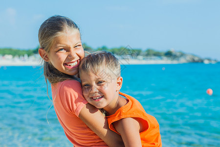 在海滩上微笑快乐的孩子女孩冒充蓝色家庭乐趣海洋金发假期阳光太阳热带高清图片素材