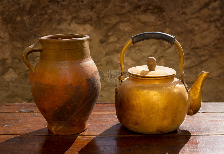 原木板和粘土罐上的古董黄铜茶壶图片