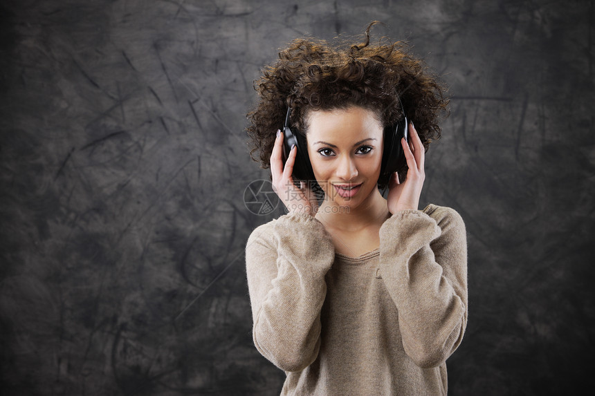 享受音乐的年轻妇女水平耳机听力女子快乐时装青少年卷发设备女性图片