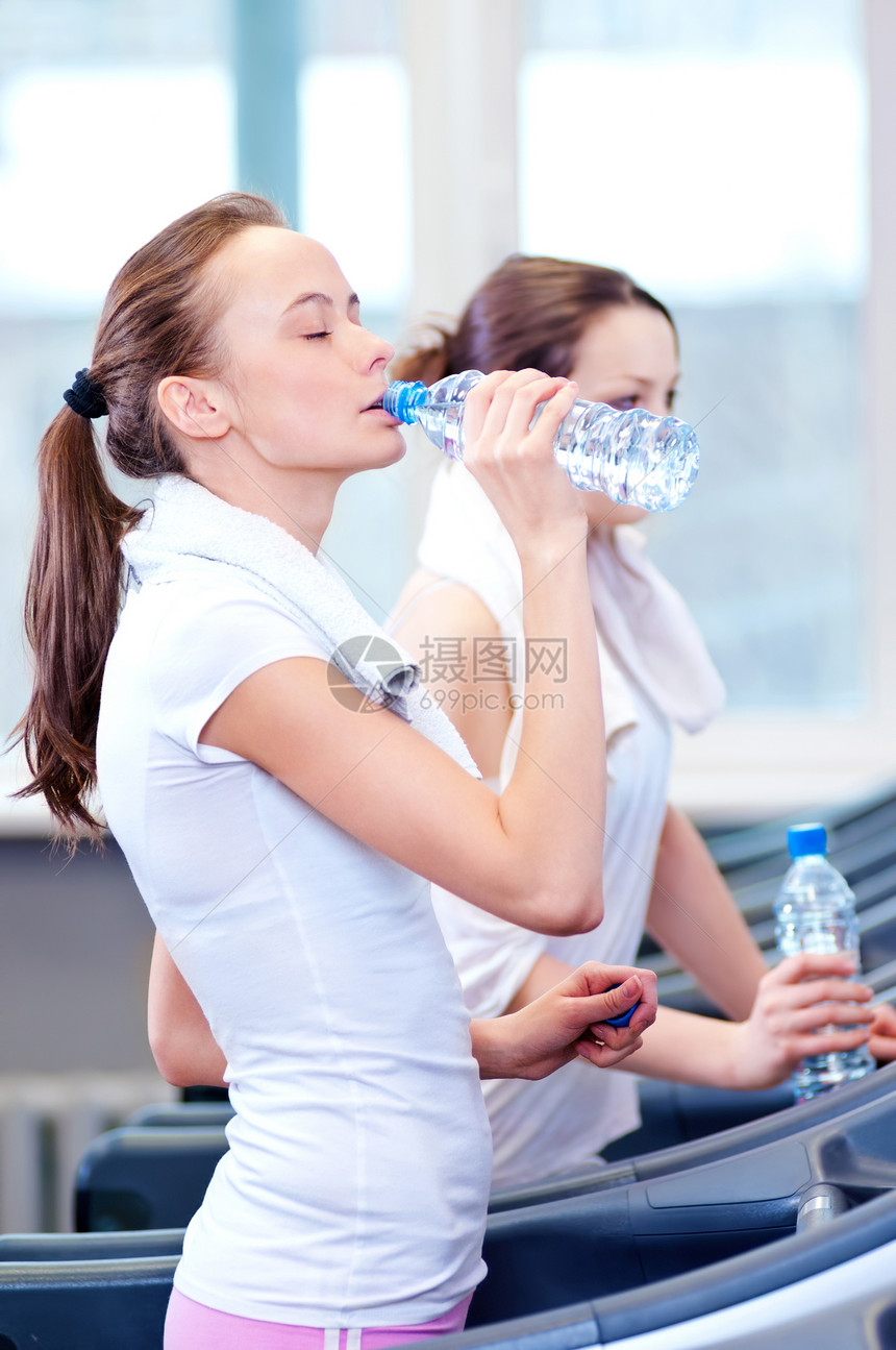 妇女运动后饮用水跑步机慢跑机器女性女士友谊健身房微笑口渴有氧运动图片