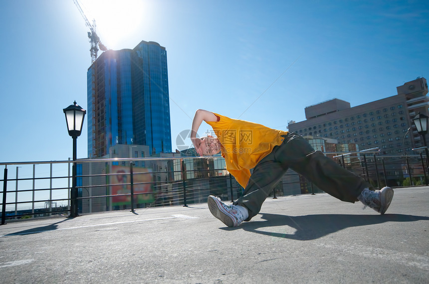 在城市风景中跳舞的青少年嘻哈女孩裤子靴子特技空气橙子射线自由房子运动光束图片