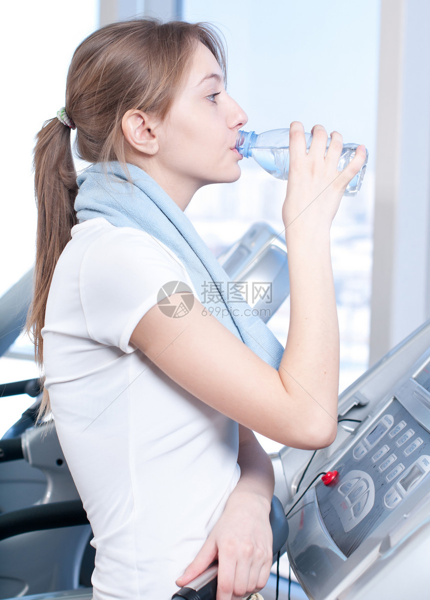 妇女在健身饮用水中的饮水力量运动跑步损失健身房蓝色福利机器有氧运动女士图片