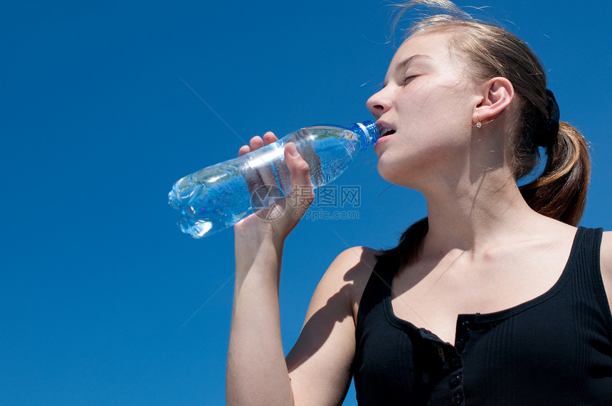 年青妇女锻炼后饮用饮用水天空女性青少年太阳运动员运动长发快乐矿物瓶子图片