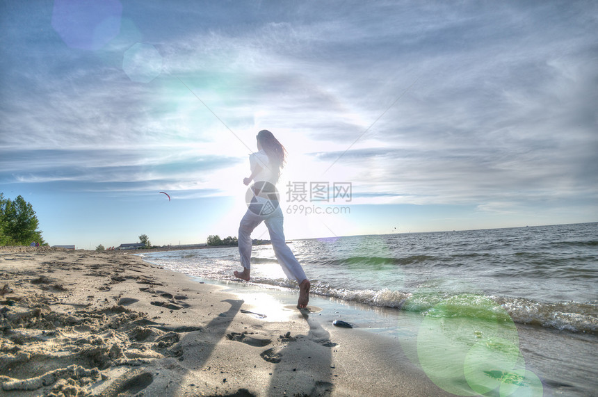 运动妇女跑在海上海岸赛跑者日落火车蓝色海滩活力女性天空太阳跑步图片