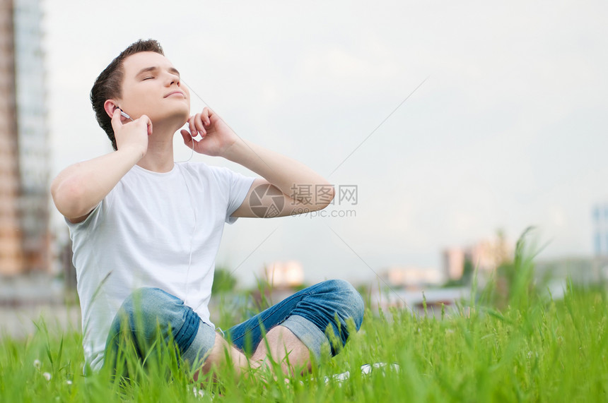 有耳机的有吸引力的年轻人生活旅游日光浴音乐播放器蓝色天空美丽男人青少年娱乐图片
