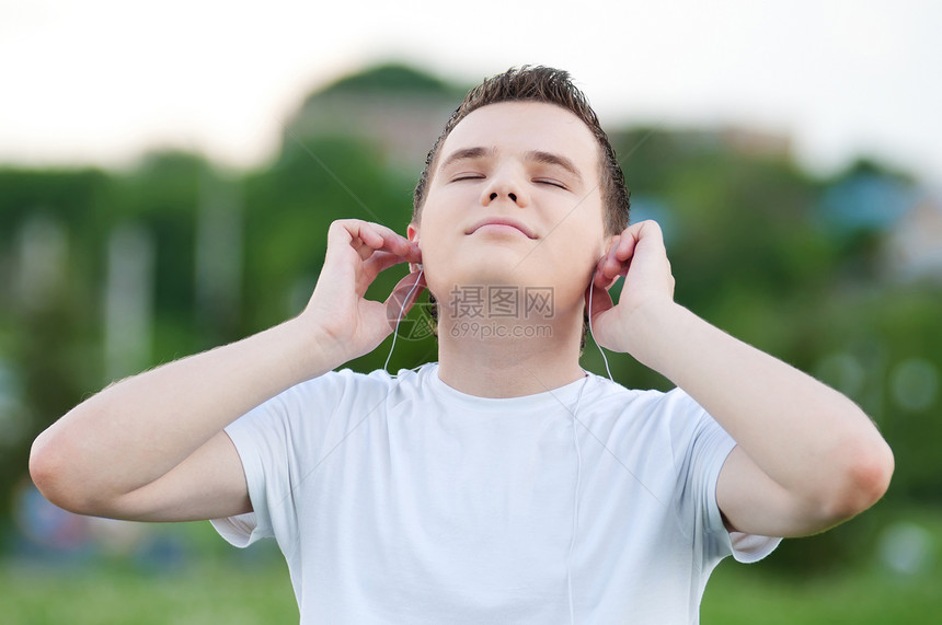 有耳机的有吸引力的年轻人自由音乐男生假期男人街道青年蓝色喜悦日光浴图片