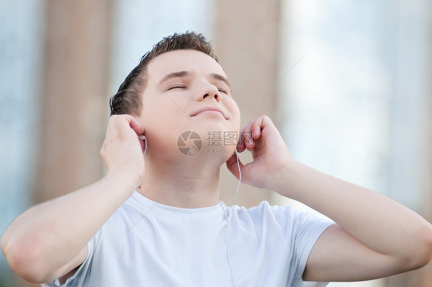 有耳机的有吸引力的年轻人自由街道蓝色男生快乐青少年天空男性公园娱乐图片