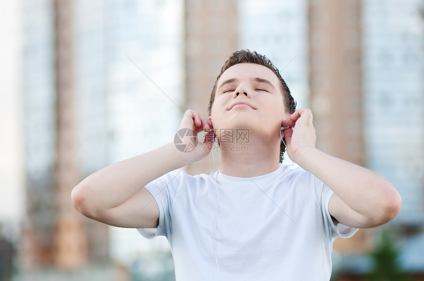 有耳机的有吸引力的年轻人男人公园乐趣闲暇音乐播放器喜悦假期娱乐音乐日光浴图片