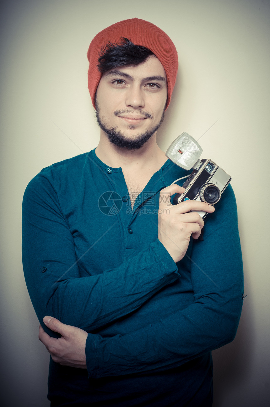 年轻时尚男子拿着旧相机衬衫工作室蓝衬衫成人发型男人照片男性老相机帽子图片