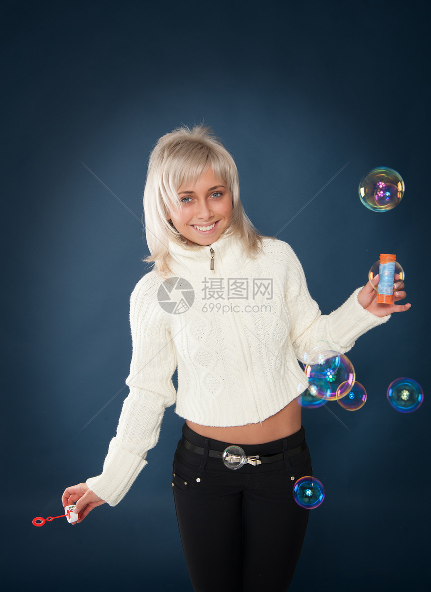 美丽的女人吹着肥皂泡泡金发肥皂水圆圈自由乐趣活动女性色彩俏皮蓝色图片