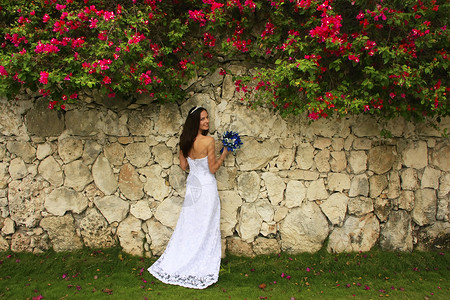 穿着婚纱的年轻女士 在石墙前摆着皇冠花束黑发热带冒充新娘花朵订婚裙子女孩未婚妻高清图片素材