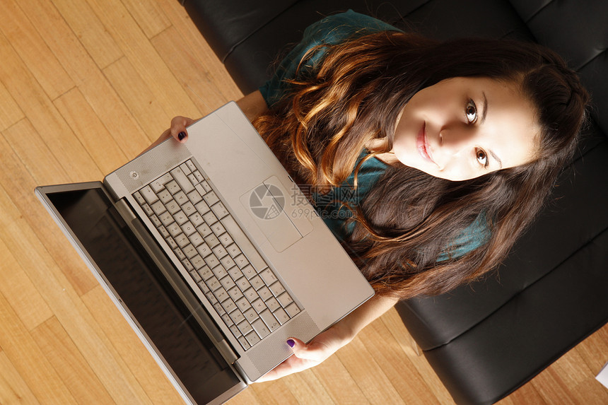带着笔记本电脑的年轻女孩女士音乐成人微笑耳机青年女性说谎皮革头发图片