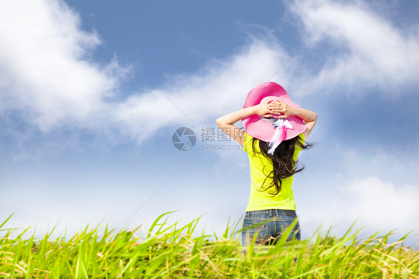 年轻女子站在草地上 看着云朵图片