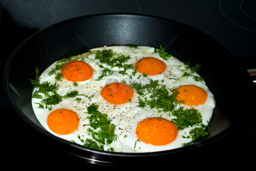煎鸡蛋在炉子里香草黄色黑色平底锅蛋黄食物图片