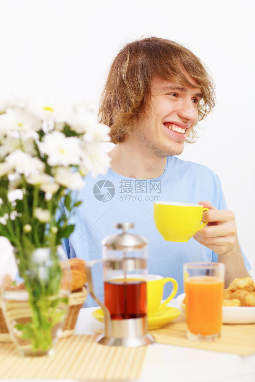 快乐的年轻人喝茶饮料微笑乐趣蓝色成人男性厨房幸福男人闲暇图片