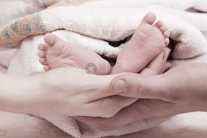 父母双手握着婴儿的腿皮肤家庭棕榈脚趾脆弱性卫生母亲父亲孩子童年图片