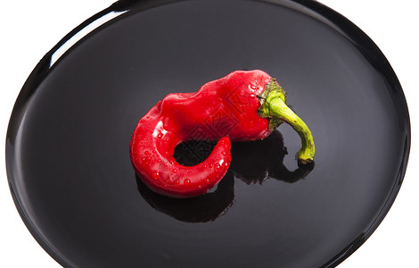 在黑盘上隔离的红鲜辣椒辣椒背景图片