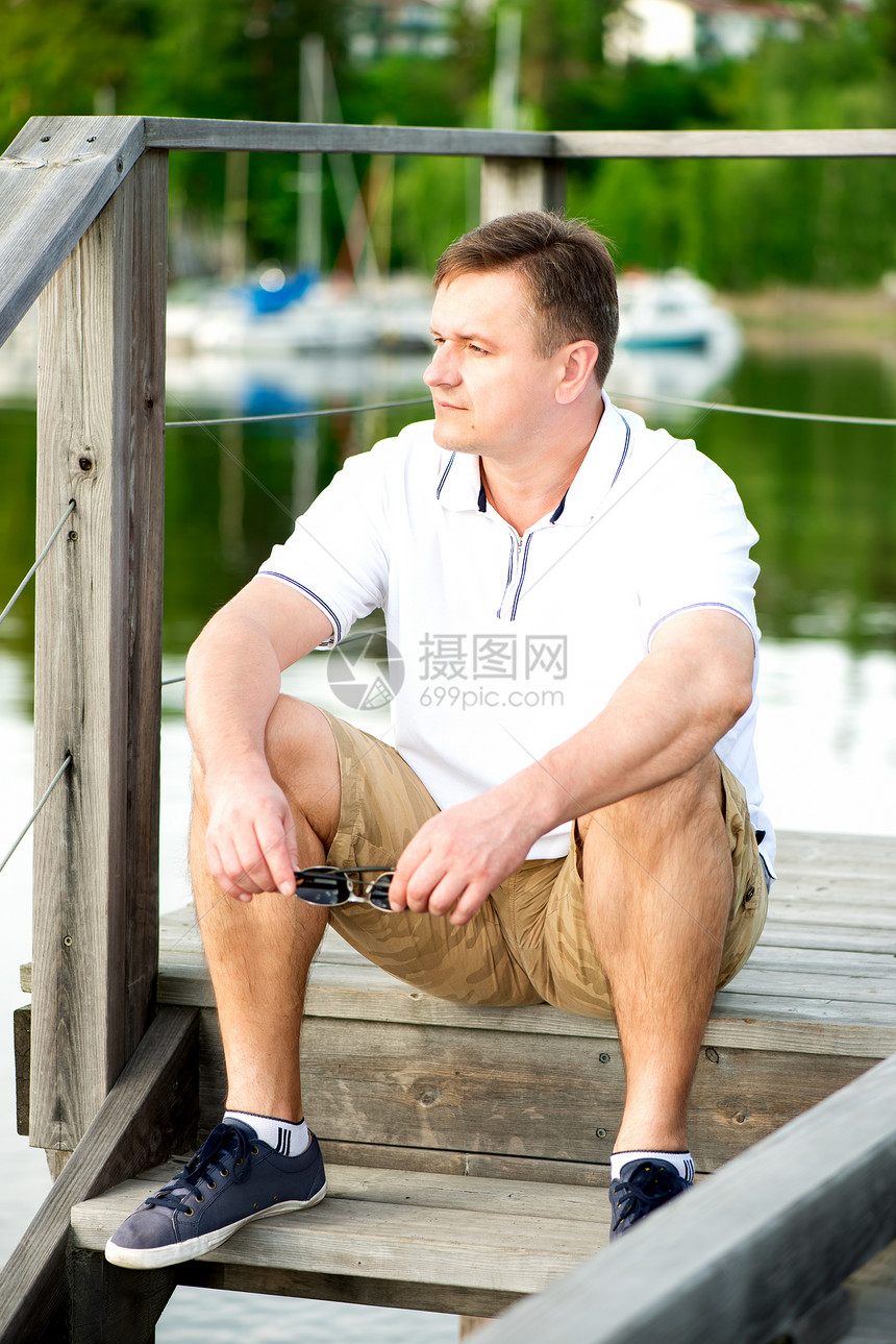 在码头坐着戴太阳眼镜的成熟男子闲暇孤独男人反射中年眼镜自由娱乐树木环境图片