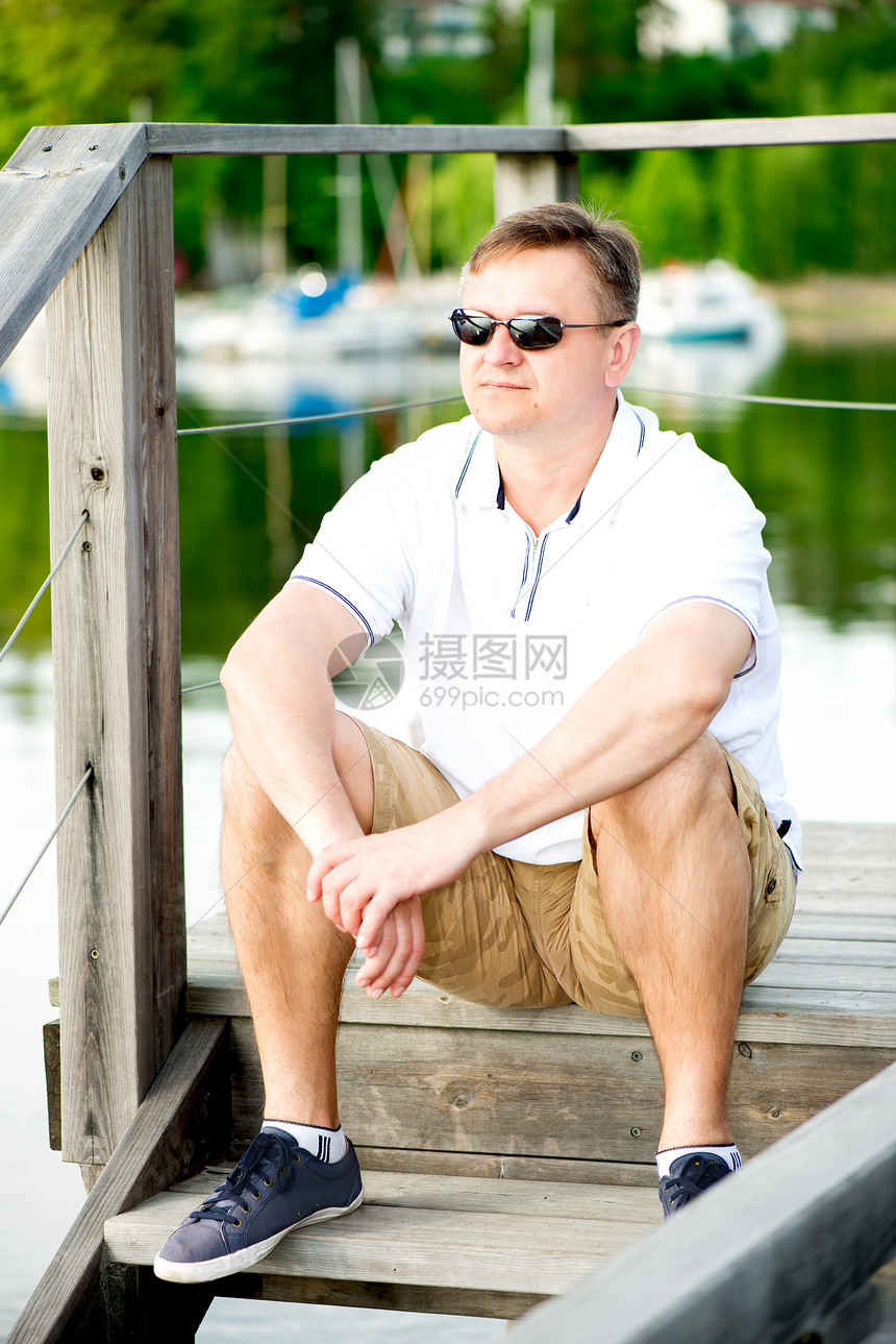 在码头坐着戴太阳眼镜的成熟男子中年树木娱乐闲暇反射男人自由码头眼镜孤独图片