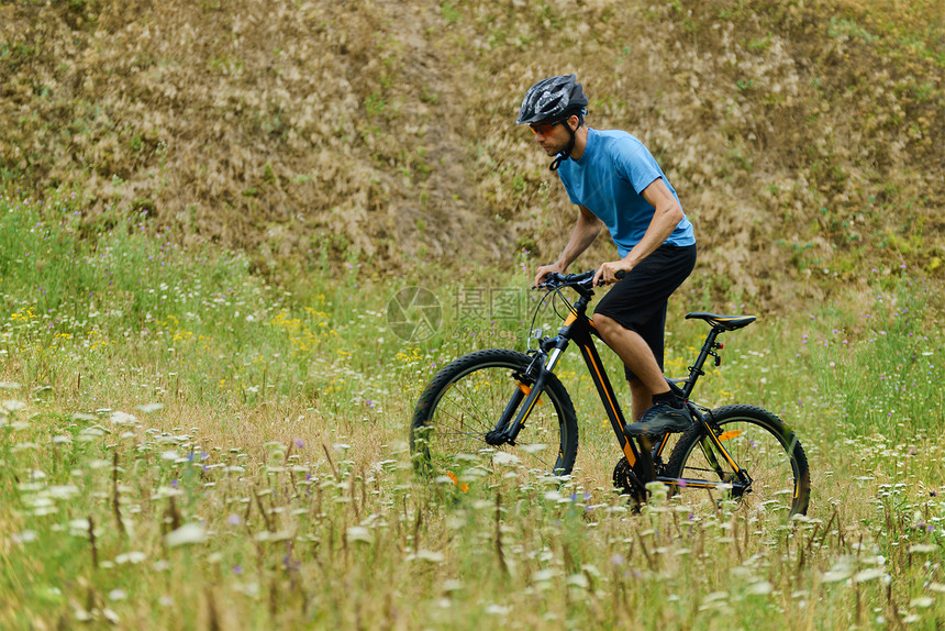 山地骑自行车通过草地骑过他的自行车图片