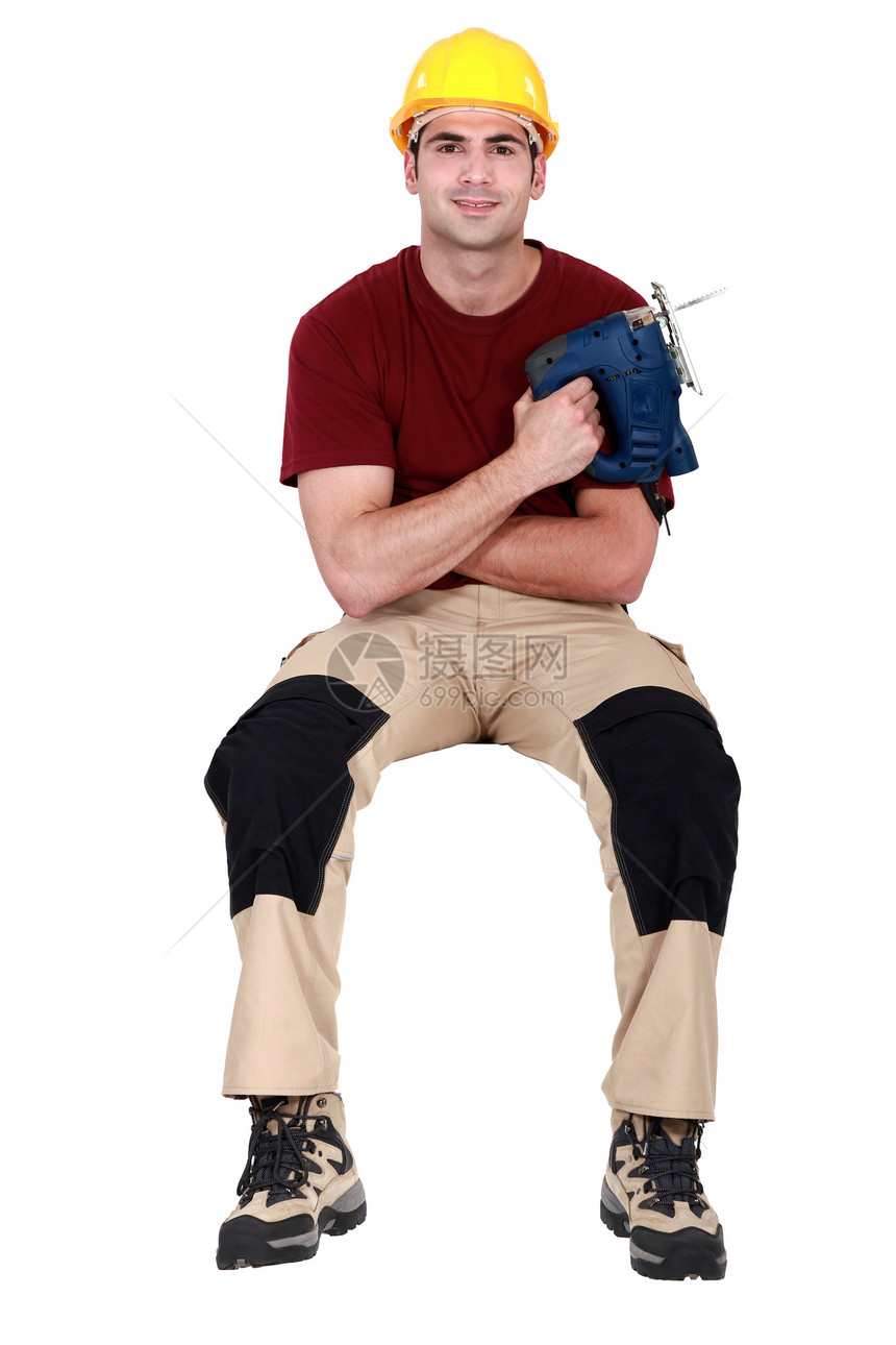男子用手持电气锯子坐着图片
