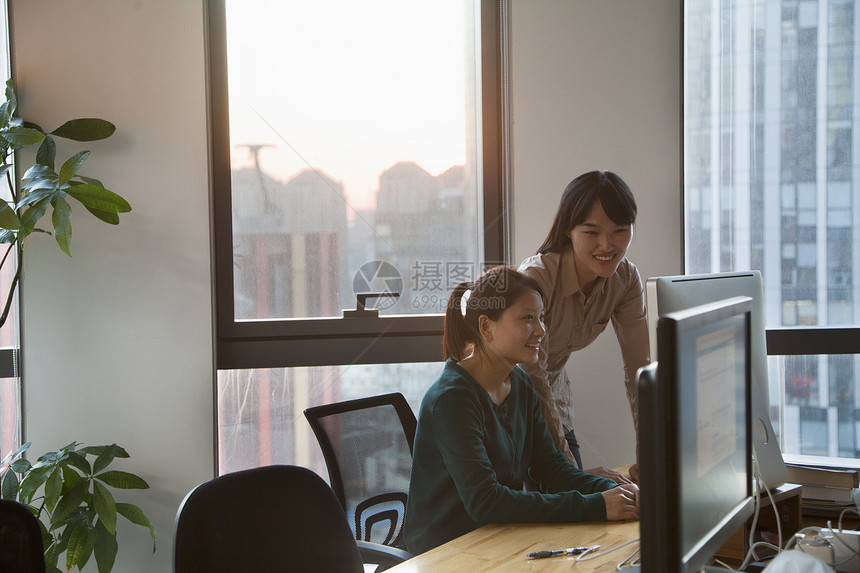 该办公室的两名女商务人士共同合作组织办公室电脑智能植物电脑显示器团结业务椅子公司收腰沟通图片