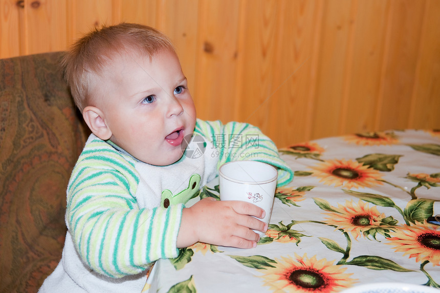 小男孩在桌边喝酒甜点牛奶孩子男孩们婴儿杯子快乐饮料食物早餐图片