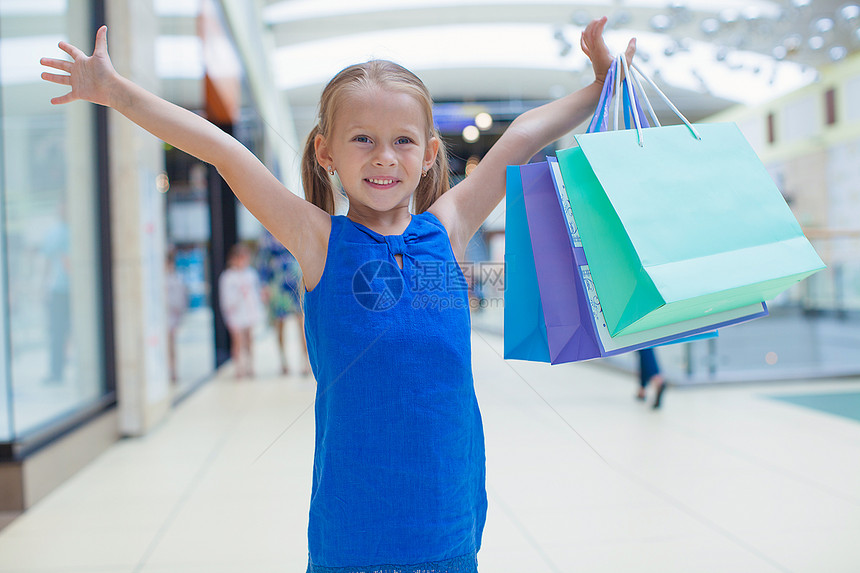 在商场上拿着购物袋的小快乐女孩的肖像生活微笑店铺销售青年女性女孩市场孩子购物中心图片