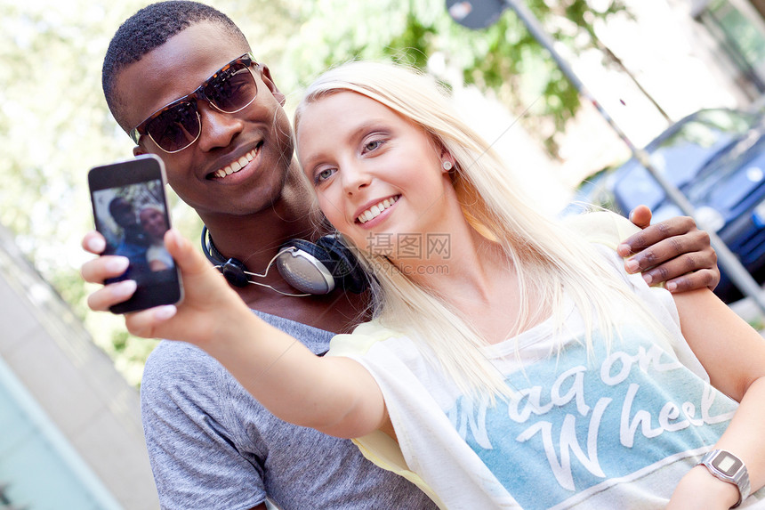 年轻笑笑多种族的情侣 用智能手机接着foto男人电话幸福女士照片乐趣男性朋友们假期女孩图片