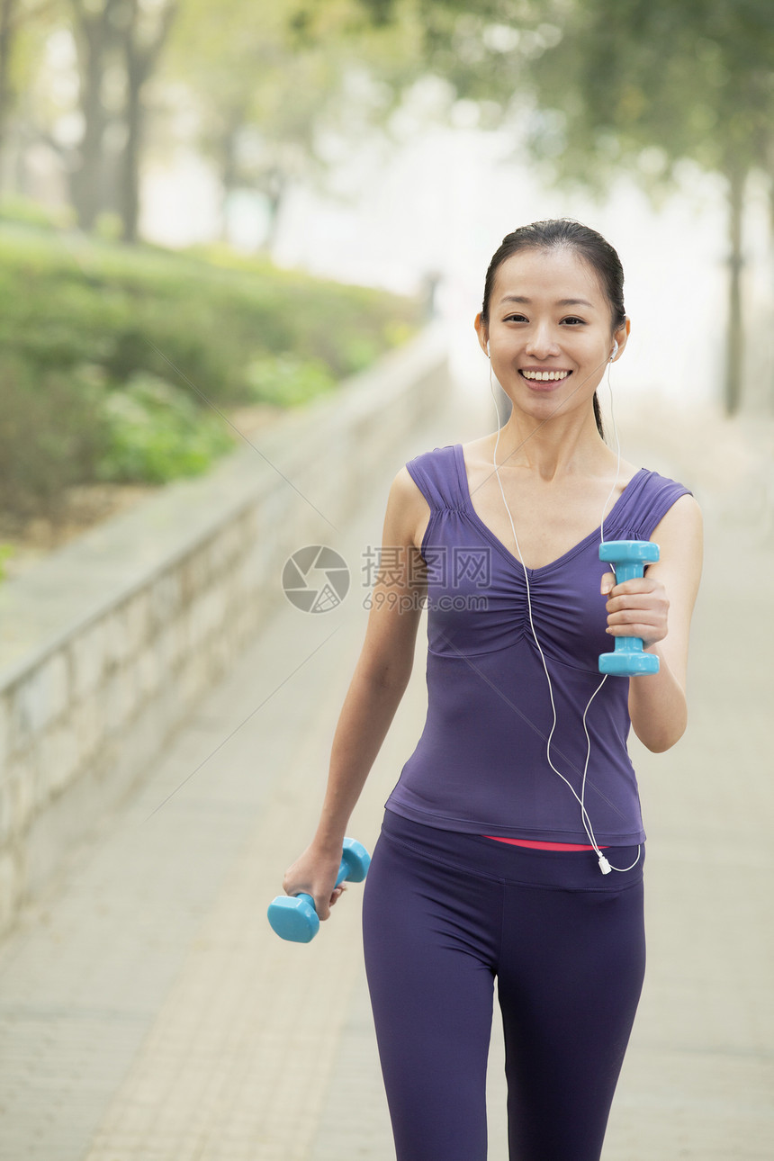 女青年在公园运动耳机享受情绪快乐训练听力微笑灵活性活动举重图片