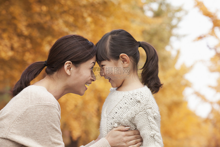 与母亲和女儿面对面保暖两个人叶子毛衣长发单亲衣物拥抱女孩们幸福