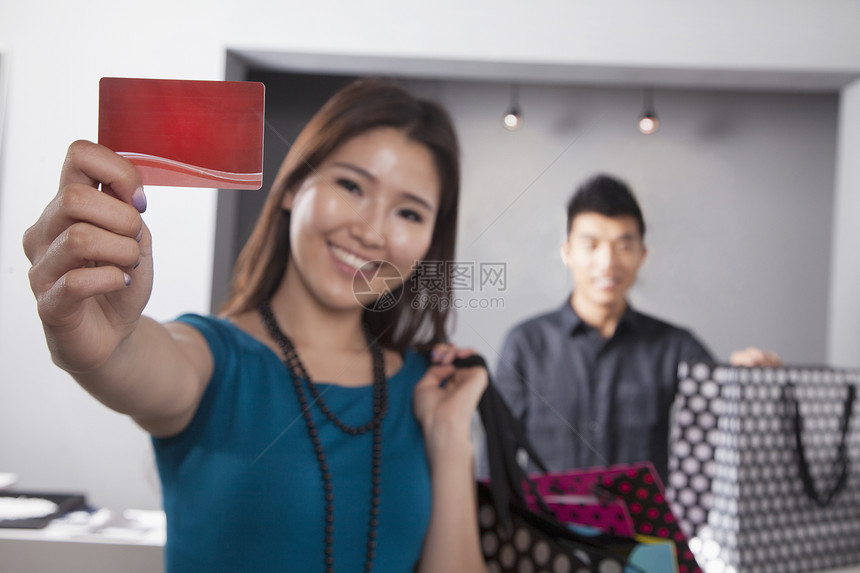 在时装店持有信用卡的年轻女性妇女图片