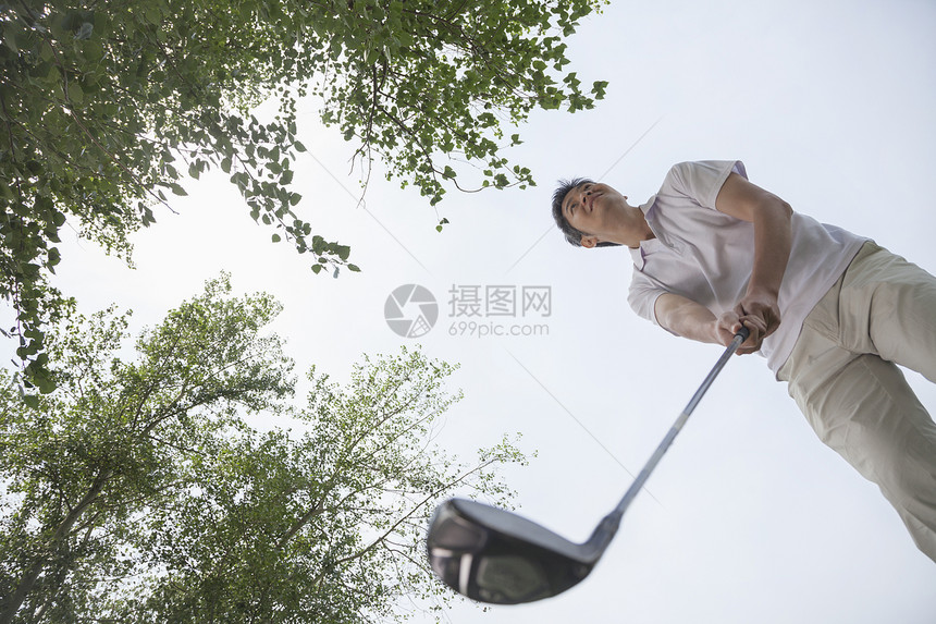 男子准备在高尔夫球场上打高尔夫球的低视角图片