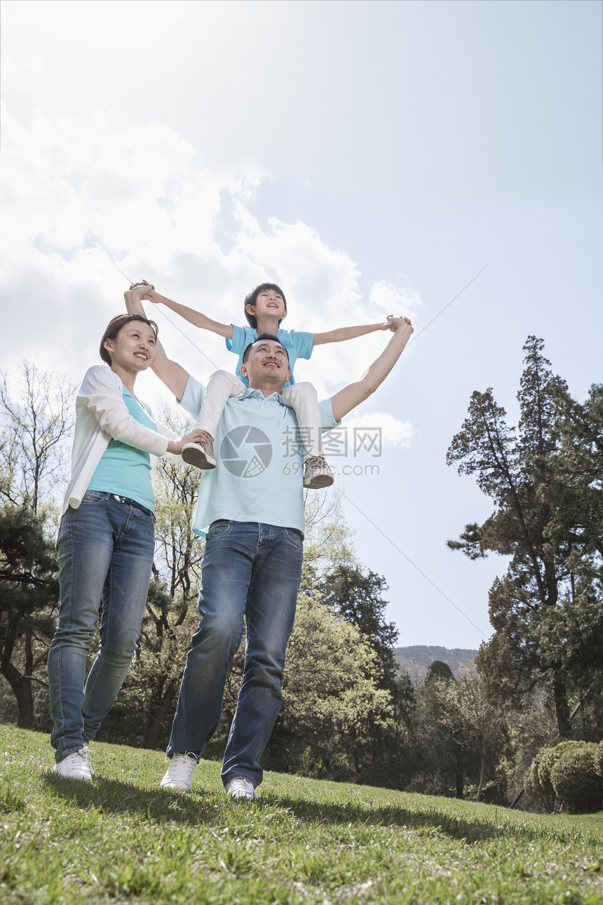 家庭在公园里 儿子站在父亲的肩膀上男孩们花园低角度团结活动母亲摄影微笑乐趣树木图片