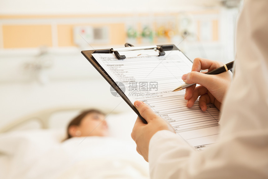 医生在医疗病历上写了近距离文章 病人躺在医院的床上 背着背景摄影工作专业疾病女性医学监视文书人类考试图片
