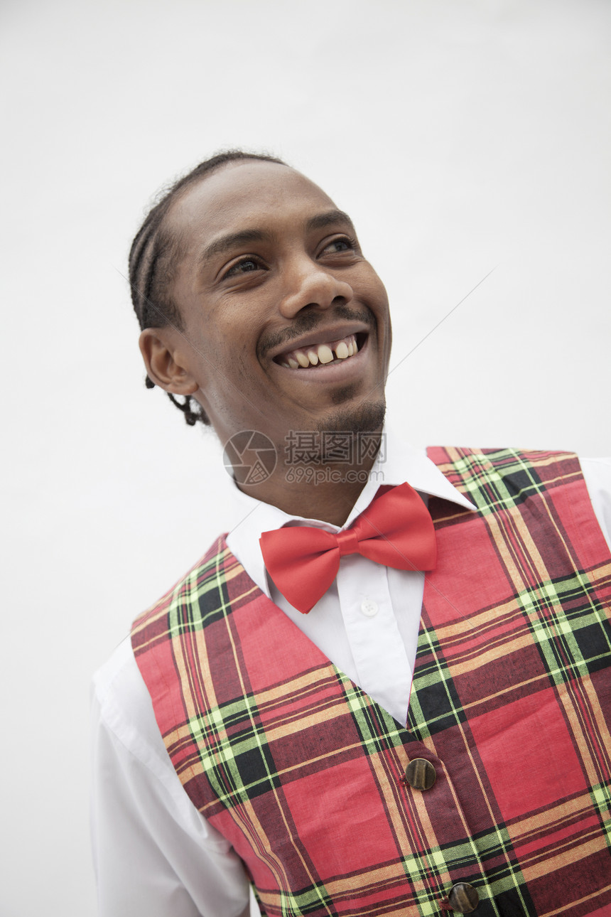 身穿格斗背甲和红领领结的年轻人肖像 摄影棚拍摄种族幸福短发微笑格子纽扣活力倾斜衬衫文化图片