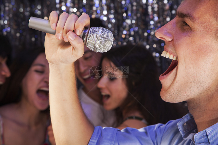 近距离的年轻人拿着麦克风 在卡拉OK唱着歌 朋友在背景中唱歌派对夜生活服装女性部位摄影活力活动音乐金发图片