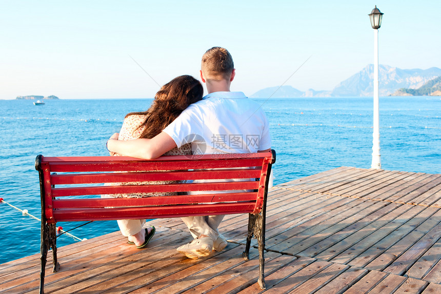 情侣坐在海边的长椅上图片