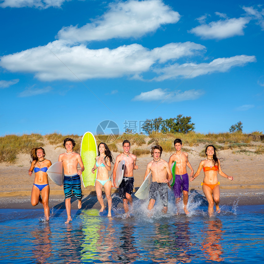 青少年冲浪者团体在海滩上喷水女性派对金发男性支撑蓝色朋友们女孩们跑步假期图片