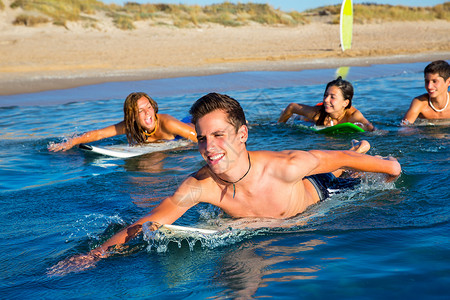 冲浪少年少年冲浪者男孩与女孩游泳游上冲浪板男人团体木板运动海滨女孩们支撑蓝色青少年男孩们背景