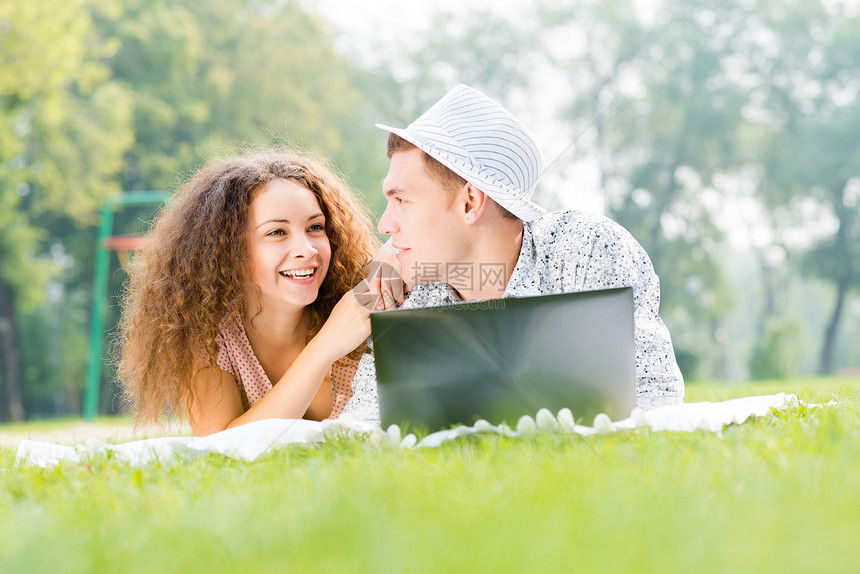 一对夫妇一起躺在公园里 带着笔记本电脑男人技术女性生活喜悦友谊闲暇女孩青年微笑图片