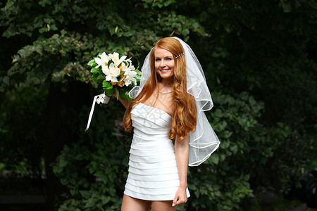 穿着婚纱的美丽红发新娘女孩女性面纱裙子花束公园礼服婚姻青年派对户外高清图片素材