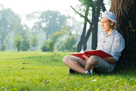 年轻人在读一本书学生幸福眼镜教育公园闲暇中学男性文学知识草高清图片素材
