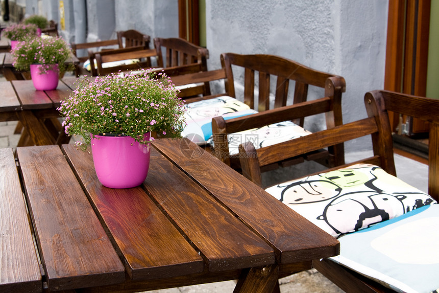 在街头咖啡厅里用鲜花和椅子的餐桌街道城市花朵花瓶粉色软垫桌子图片