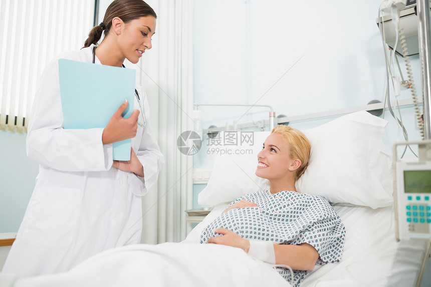 产科医生与一个微笑的怀孕病人交谈图片