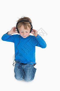 通过耳机监听音乐的年轻男孩享受男生爱好童年金发女郎浅色头发金发牛仔裤娱乐背景图片